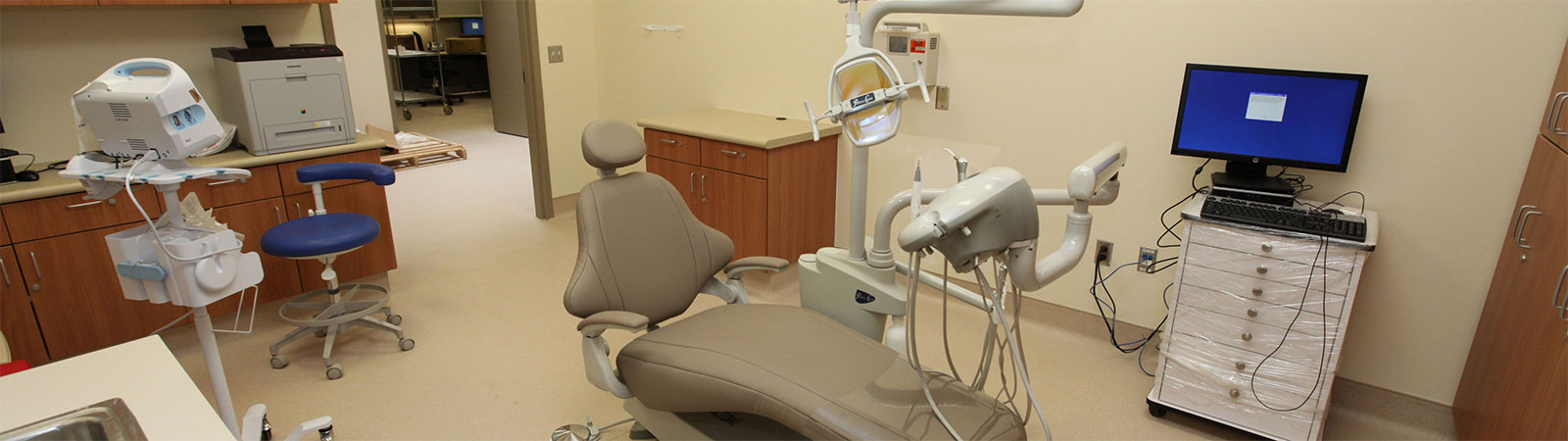 Various dental equipment, including a chair, mounted light and a computer monitor, at a CCHCS institution